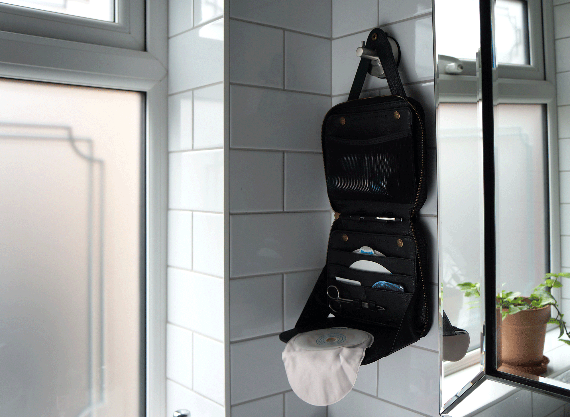black stony case hung up in bathroom with colostomy bag